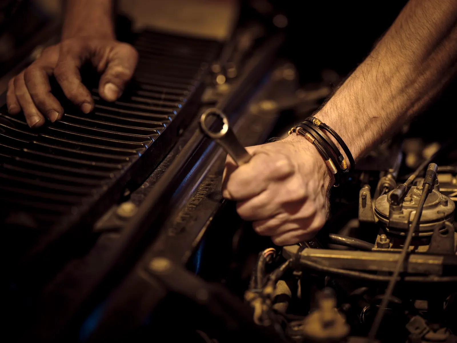 Hands using a socket wrench in an open engine bay